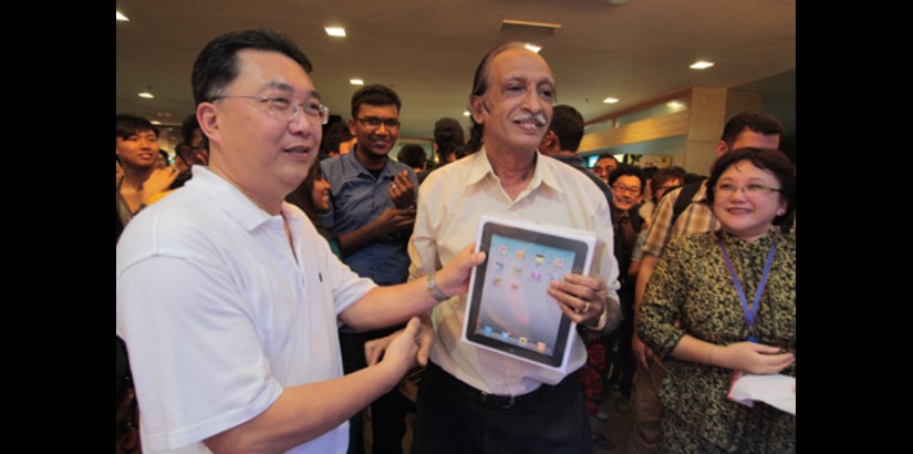  Mr Pakiraji @ Pakiraju s/o S. Ramaya receives the i-pad he won from Mr Lee Thuan Teik, while Prof. Dr. Lee looks on.